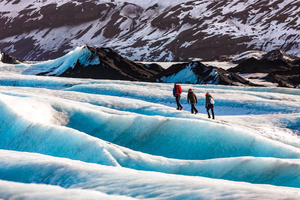 Prive gids en een paar wandelaars wandelen op de gletsjer bij Solheimajokull