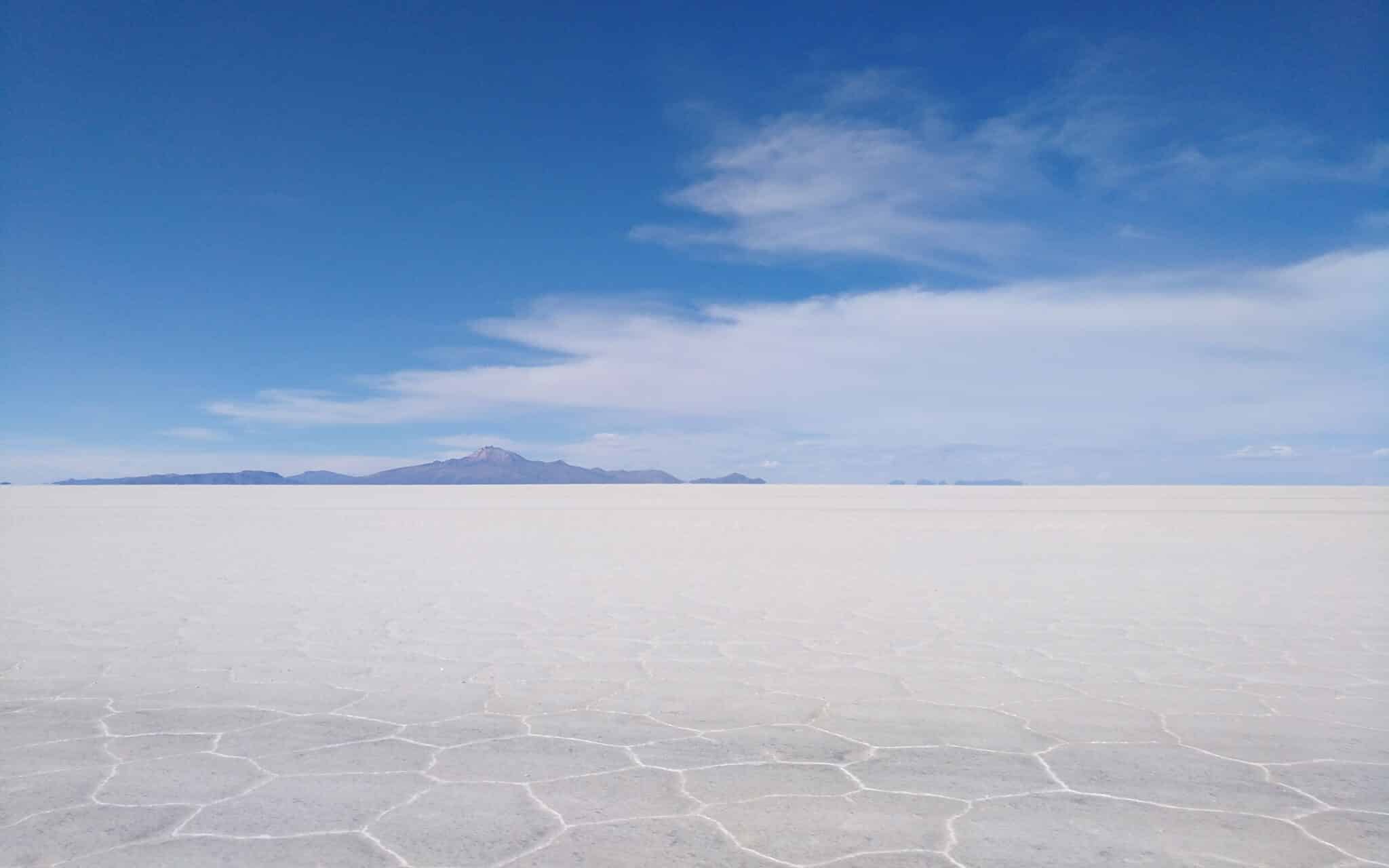 Der Salar de Uyuni, im Vordergrund gut erkennbar die Salzkruste als Boden, am Horizont Berge.