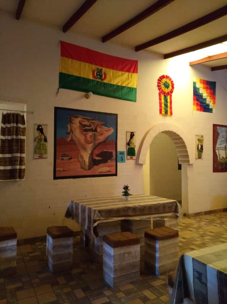 L'area pranzo dell'Hotel del Sale, la bandiera boliviana sul muro, un dipinto dell'albero pietrificato e altre decorazioni tradizionali.