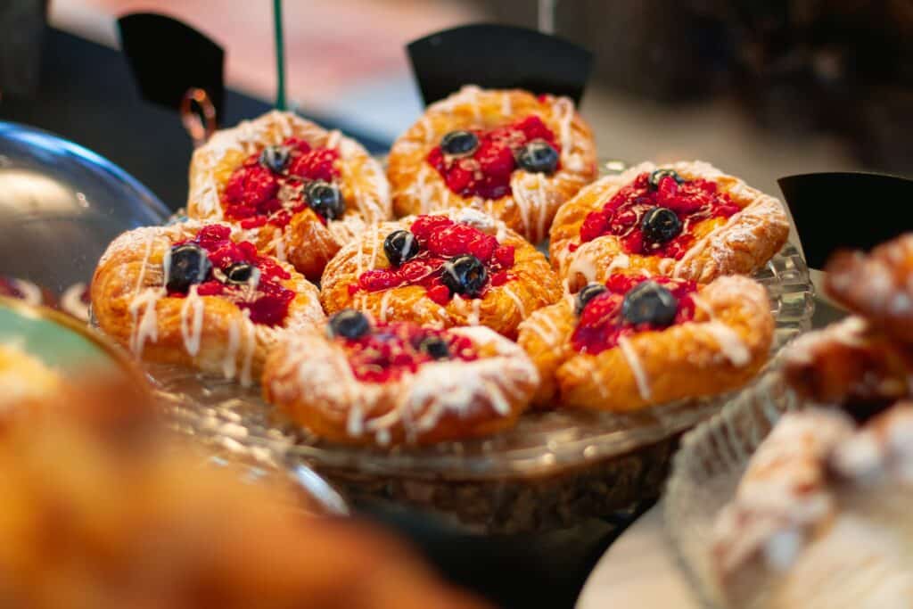 The picture shows a plate with pastries. These are decorated with fresh berries and icing.