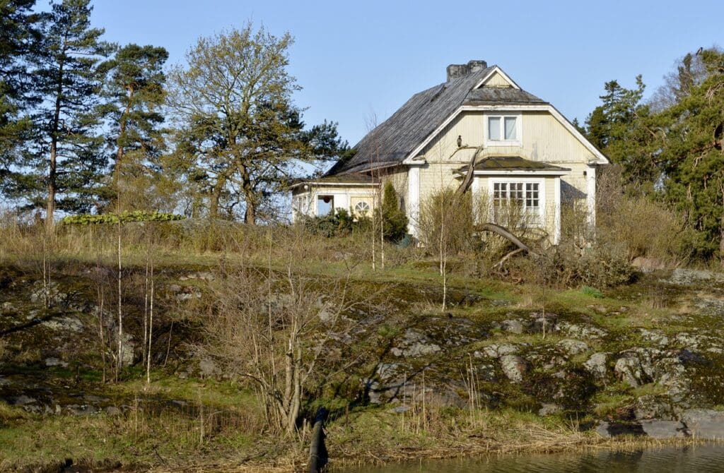 L'image montre une maison en bois finlandaise traditionnelle dans la nature.