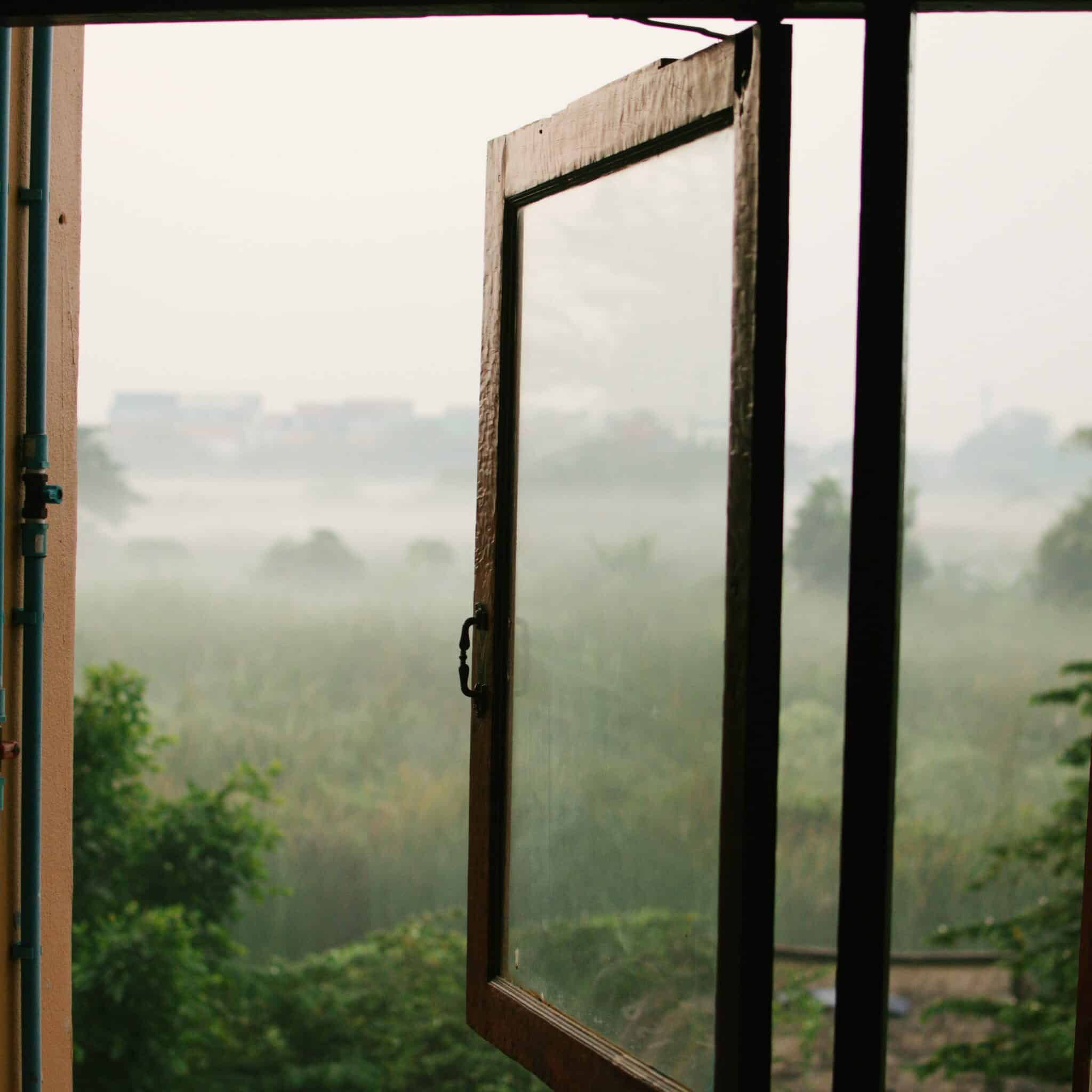 Een open raam biedt uitzicht op een theeplantage.